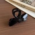 Eleganter schwarzer Schleifen-Haarclip mit goldener Schrift auf einer Holzoberfläche - Glänzend Schwarz