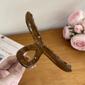 Grande molletta per capelli in resina ambrata con manico rotondo su fondo in legno - Marrone