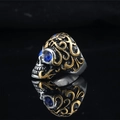 Anillo de calavera gótica bicolor con ojos de piedras azules sobre un fondo negro mate - US 7 / Oro Azul