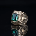 Vintage eagle titanium steel ring with emerald green stone on black reflective background - Gold Tone Green Gemstone
