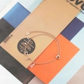 Pulsera de doble capa en oro rosa con dijes de estrella y corazón sobre fondo revista - Oro rosa