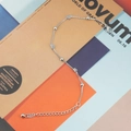 Minimalistische titaniumstalen armband met hart- en kraalhangers op een tijdschrift - Staalkleur