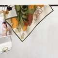 Elegante zijden sjaal met groene bloemenprint en gestreepte randen aan een kledingrekje - Vierkant / Groen