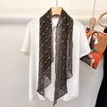 Detail of silk scarf with geometric blue patterns on sheer black fabric draped on a shirt - Caramel Floral