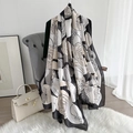 Elegant black and white camellia print silk scarf draped over a modern grey chair - 180*90 / Black