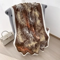 Châle long marron avec motifs de plumes et bordure blanc crème sur un fauteuil - Grand / Marron