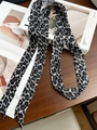 Narrow silk twilly scarf with black and white leopard print draped on art books - Grey Leopard