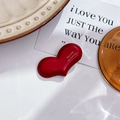 Detailed view of a red heart-shaped resin hair clip with golden script on a stylish desk - Dark Red (4.3cm)