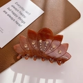 Bernsteinfarbene Lotus-Haarklammer mit Kristall-Strass auf edler Lederoberfläche - Braun