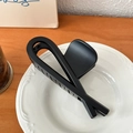 Minimalist matte black hair claw clip with cross loop design on a decorative ceramic plate - Matte Black-12cm