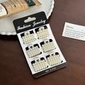 Lot de six mini pinces à cheveux en perles sur une carte noire sur une table en bois - Ensemble 23