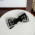 Elegante pinza para el pelo con lazo de terciopelo negro y perlas en un plato decorativo - Pinza para el Cabello con Lazo de Perlas