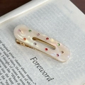 Fermaglio ovale in resina color crema con strass colorati su pagine di libro - Bianco Iridescente