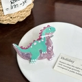 Süße Haarklammer aus Acryl im Dinosaurier-Design in Grün und Lila auf Keramiktablett - Cyan