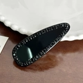Barrette goutte noire élégante avec strass brillants sur fond en bois naturel - Noir