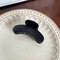 Matte black curved shark hair claw clip displayed on a minimalist ceramic plate - Black Curved - 8.3cm