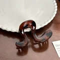 Elegant dark brown tortoiseshell hair claw clip with a wave-shaped design on a ceramic plate - U-Shaped Dark Coffee (8cm)