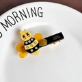 Cute bee hair clip with yellow rhinestones and X-shaped eyes in a white dish - Orange Bee Hair Clip
