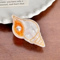 Schicke Haarspange aus Acetat in Muschelform mit Perlendetail und Küsten-Ästhetik - Schnecken-Stil