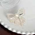 Elegant pearlescent acetate bow hair clip with iridescent finish on a white ceramic plate - Iridescent White Hair Clip