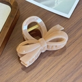 Elegante haarclip met roze strik in glanzende acryl afwerking op een houten bureau - Nude-8cm