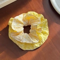Elegante coletero amarillo con flores y cuadros sobre una superficie de madera - Estilo Floral Amarillo