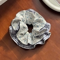 Coletero de tela azul con flores y cuadros sobre una superficie de madera - Estilo Floral Azul
