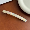 Elegant iridescent acetate spring hair clip with a pearlescent finish on a wooden desk - 10.6cm / Iridescent White