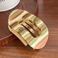 Matte beige oval hair claw clip with colorful abstract patterns on wood tray - Green & Brown