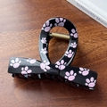 Medium bow-shaped black hair claw clip with pink cat paw prints on a wooden surface - Black-Bow