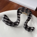 Minimalistische S-förmige Haarklammer mit schwarz-weißem Gingham-Muster auf Porzellanplatte - Geometrischer Wellenstil / Schwarz