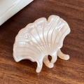 Elegant scalloped hair claw clip in pearlescent cream white finish on wood surface - Beige