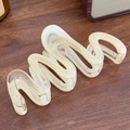 Elegant cream wavy hair claw clip with pearlescent finish on dark wood surface - Snake Beige