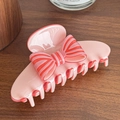 Elegant pink hair claw clip featuring a striped ribbon bow on dark wood surface - Pink Orange Claw Clip