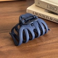 Matte navy blue shark hair claw clip for thick hair styling on a wooden desk - Navy Blue
