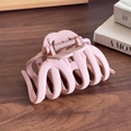 Matte light pink claw clip with multi-tooth design on a dark wood background - Pink