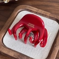 Glossy red acetate shark hair claw clip with gold branding and multi-tooth design - Red
