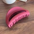 Matte fuchsia siliconen haarklem met uitgesneden ontwerp op donker houten achtergrond - Rood