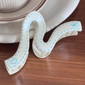 Creamy white S-wave hair claw clip with blue heart patterns and a matte resin finish - Off-White Snake Shape