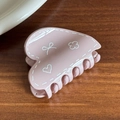 Pink heart-shaped hair claw with white hand-drawn bow and floral patterns on wood background - Pink Heart Shape