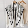 Dettaglio elegante sciarpa di seta bianca con motivi di corde e nappe nere su una gruccia - Bianco