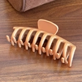 Matte nude large silicone hair claw clip for ponytail on dark wooden surface - Shark Clip-Coffee