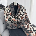 Leopard print pashmina shawl in white and orange cashmere-like knit on a black hanger - Long Tassel Style / Gray