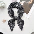 Detailed close-up of a paisley square scarf tied in a bow with elegant French vintage decor - 68*68cm / Black