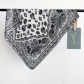 Gros plan du motif paisley classique et des fleurs sur un foulard carré élégant - 68x68 / Noir