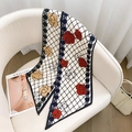 Détail de la texture d'un foulard en soie rétro avec imprimé camélia drapé sur un canapé - Petite Fleur Rouge