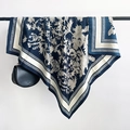 Detail eines Seidenschals in Marineblau und Beige mit Blumenmuster an einer Stange - 90x90cm / Blau