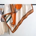 Detail van een oranje zijden sjaal met ruitermotief hangend aan een witte muur - 90*90cm / Oranje
