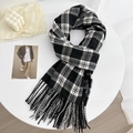 Classic black and white checkered scarf with soft fringe tassels on a white table - Black