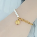 Gouden ketting en parelarmband met een lachend gezichtje aan een vrouwenpols getoond - Goud